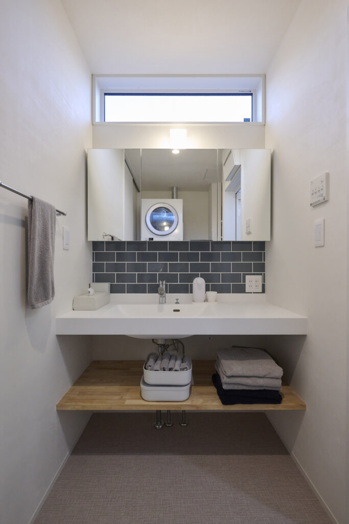 スモーキーなタイルがよく似合う洗面スペースの計画　ボウルと一体成型のカウンター