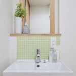 造作洗面台には天然木フレームの鏡と若草色のモザイクタイル
