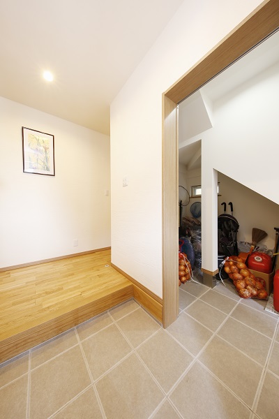 親世帯と子世帯をつなぐ土間空間。階段下のデッドスペースを有効に利用した収納スペースもあります。