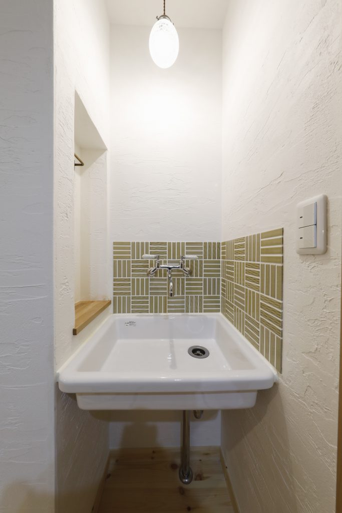 トイレ近くの簡易洗面台横の隙間もニッチにしてタオルハンガーや小物も置けるように施しました。