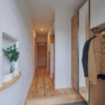 さりげなく弧にデザインしたニッチ ロールスクリーンを施したコート掛け