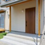 洗い出し仕上げと鎖樋が調和し、印象的な玄関ポーチ