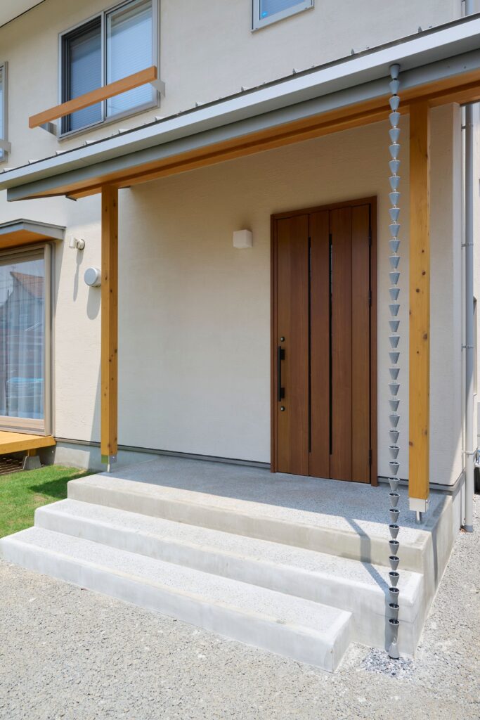 洗い出し仕上げと鎖樋が調和し、印象的な玄関ポーチ　