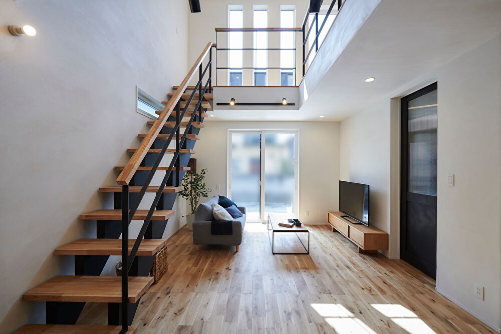 南面の吹抜けから明るい陽光がこぼれるリビング<br />
