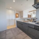 グレーブラックのキッチン＋モルタル調の床　トレンド感あふれる空間