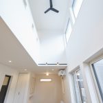 吹抜の大空間には空気を循環するシーリングファン 2階廊下にはのぞき窓を配し遊び心を