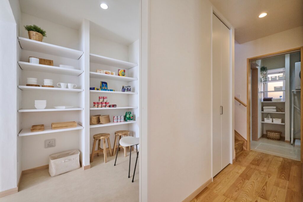 キッチン横のパントリー　回遊動線の先に見えるのはランドリールームの収納