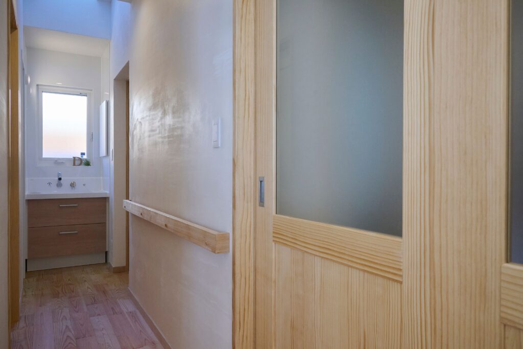 天窓からの陽光が明るい洗面台、建具に合わせた握りやすい天然木の手摺は、お母様を想う設えに