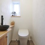 トイレ造作カウンターには黒の水栓、ボウルを合わせて 窓からの光に漆喰の陰影も美しく