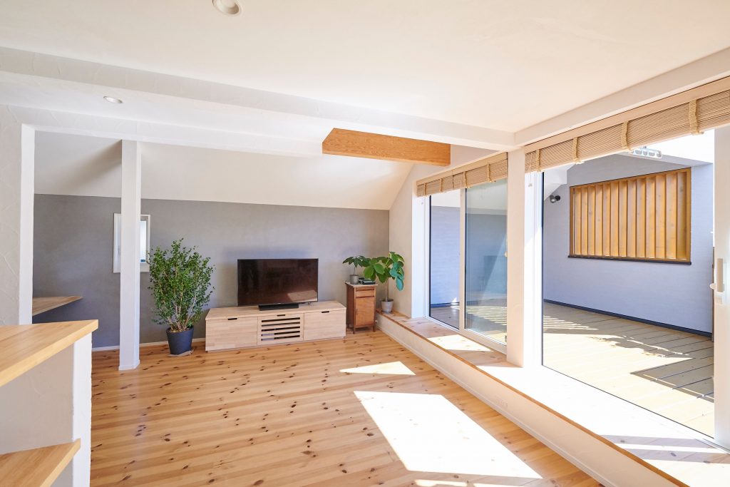 リビングから外部へと続く壁面をグレーのスタッコフレックスで仕上げ、空間に広がりを持たせました　<br />
バルコニーに斜めに配置したフェンスが光と風を取り込みプライベートを守ります